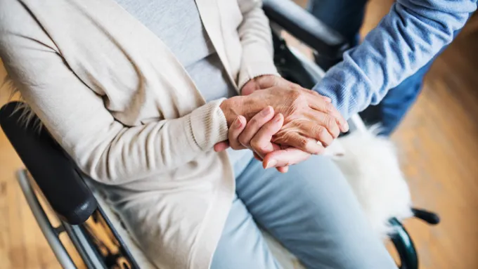 A closeup of a woman holding hands with a companion.