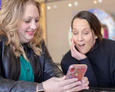 Photo of JoAnn Jensen showing a photo on her phone to Lori Platt, MD