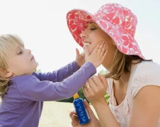 Girl putting sunscreen on mom