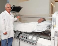 Dr. Keith Leatherbury stands near hyperbaric oxygen chamber