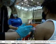 Screen grab from TV story of a young man getting a COVID shot