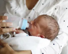 Newborn drinking from bottle in maternity ward