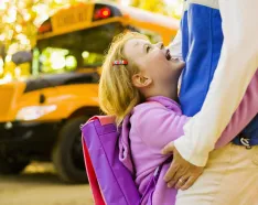 Girl with mother near school bus