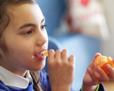 Elementary school student eating orange