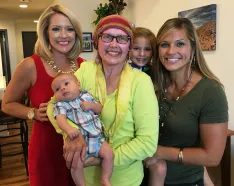 Cancer Survivor Amy Vogt and her family pose with WOWT's Malorie Maddox
