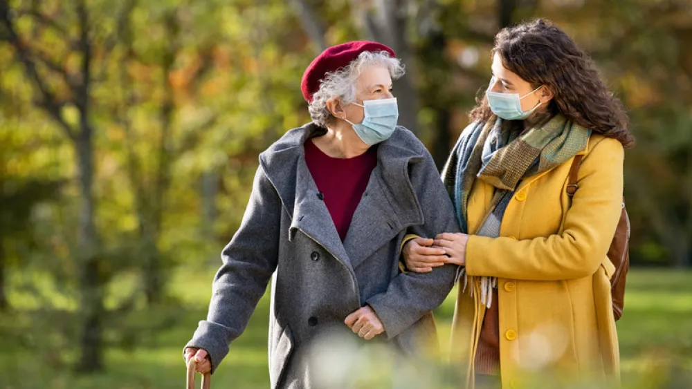 Older woman walking with young woman in park