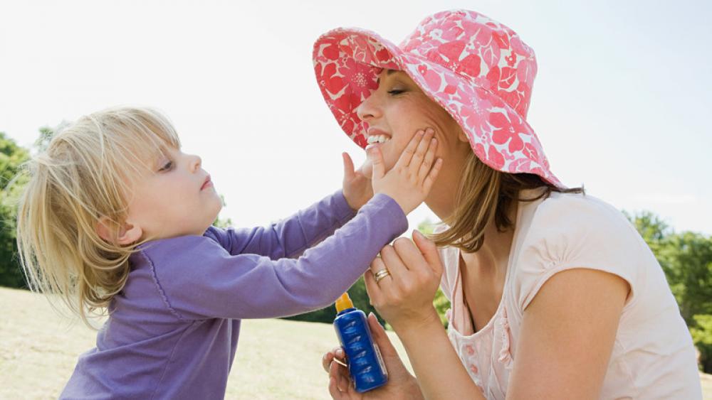 Girl putting sunscreen on mom