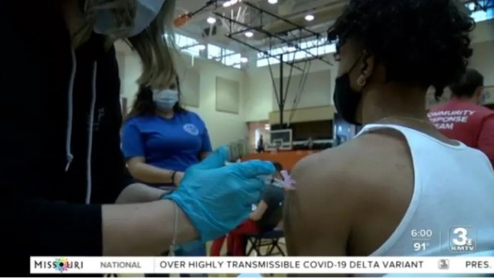 Screen grab from TV story of a young man getting a COVID shot