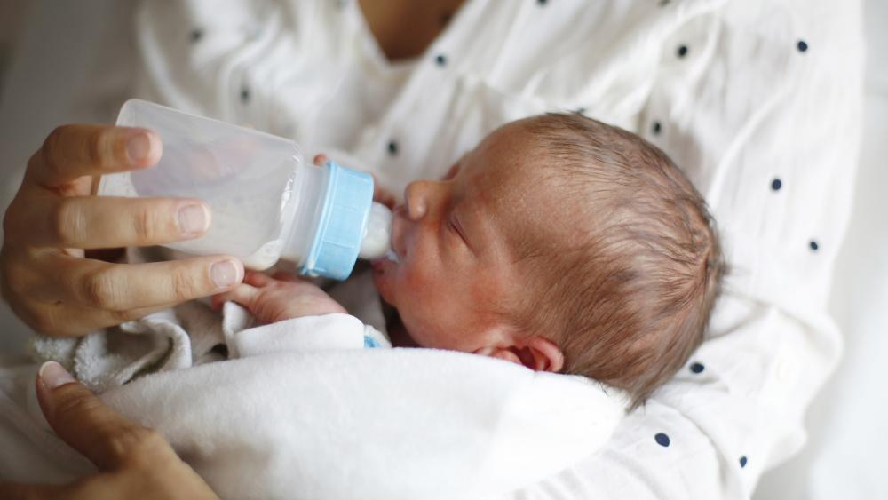 Newborn drinking from bottle in maternity ward