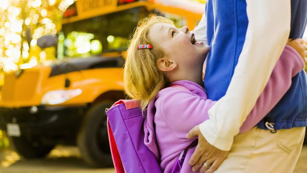 Girl with mother near school bus